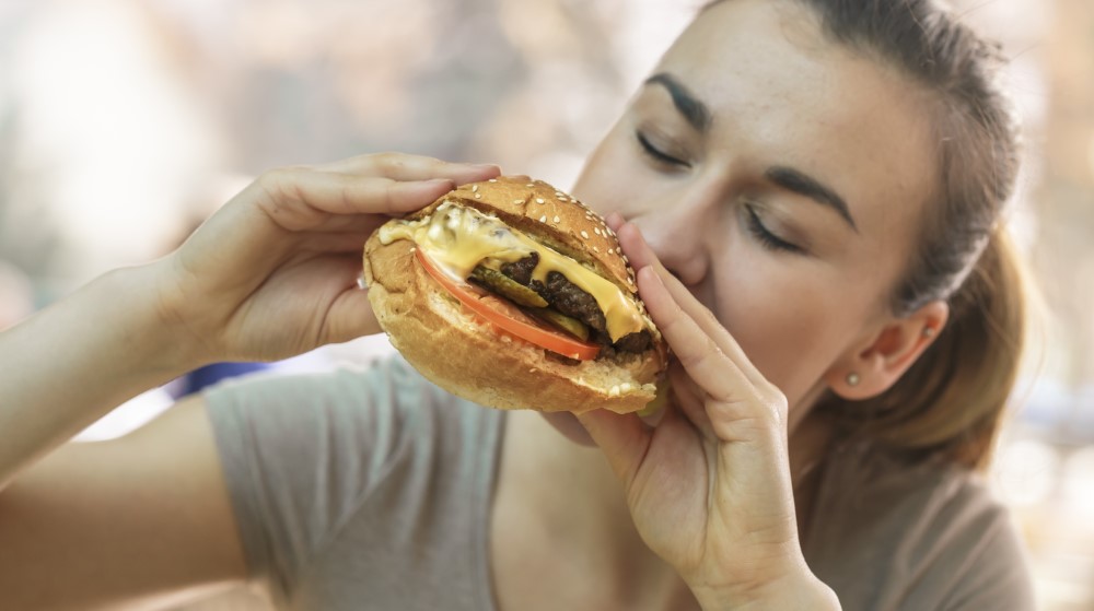 young woman cafe eating tasty sandwich
