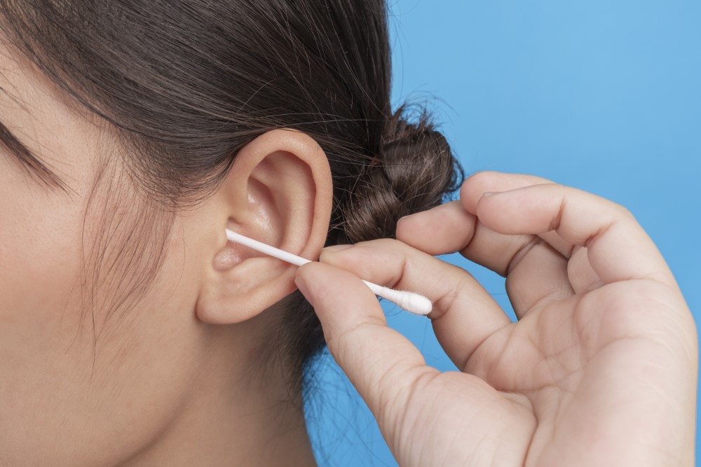 young girl is ear picking with cotton swab blue wall studio