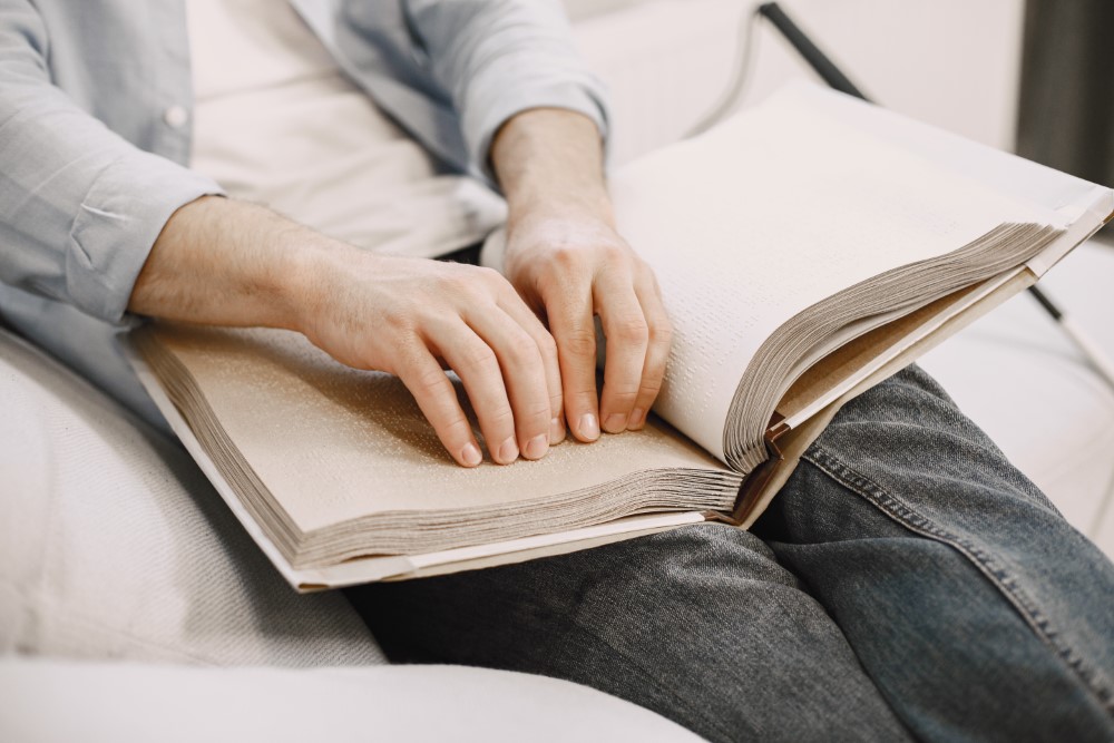 blind man reading braille book couch disabled people