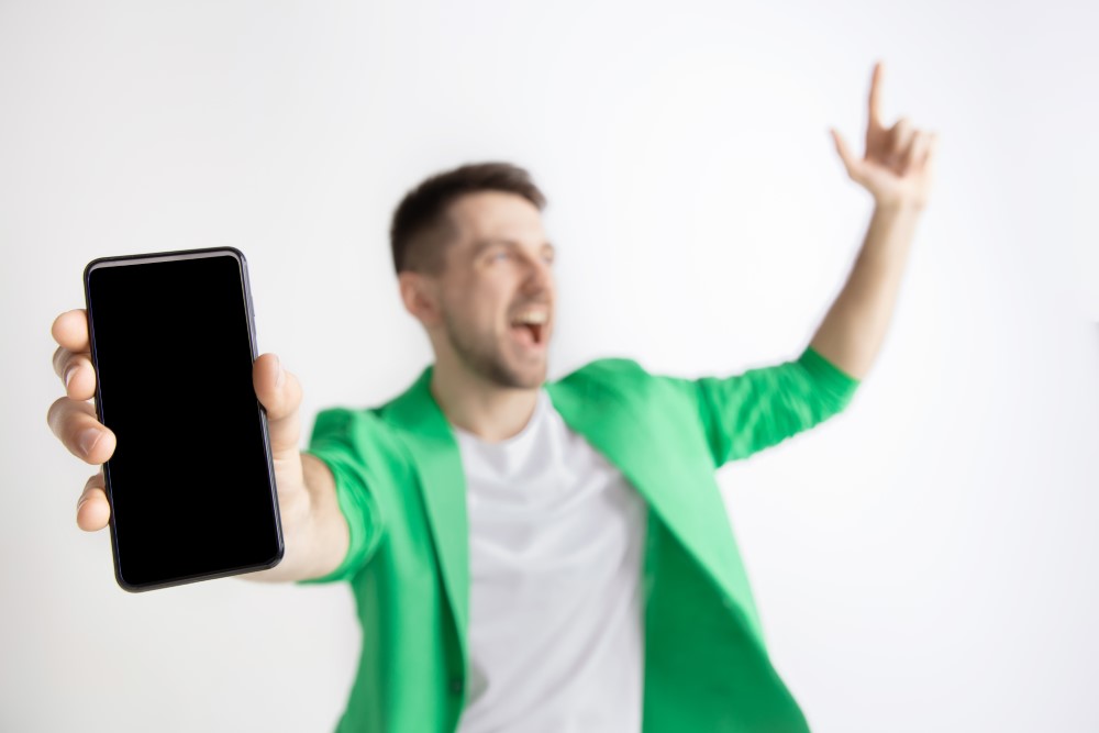 its cool good news that like me young handsome man showing smartphone screen signing ok sign isolated gray background human emotions facial expression advertising concept