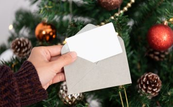 hand holding mockup christmas greeting card invitation design christmas tree background